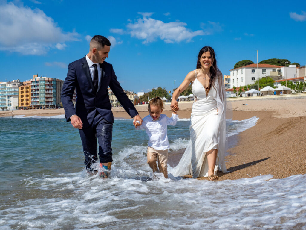 La família caminant i jugant a la platja amb alegria.